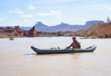 Kayaker admiring the scenery with the bluffs and spires of Castle Valley in the background in Moab, Utah - Mild to Wild