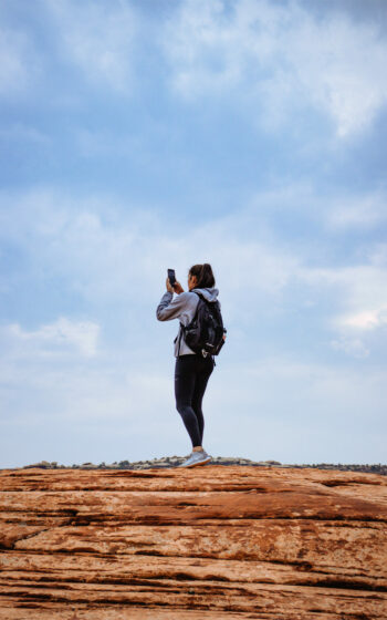 Woman Taking Photo Hiking At Gemini Bridges - Moab, Utah - Mild to Wild Rafting & Jeep Tours