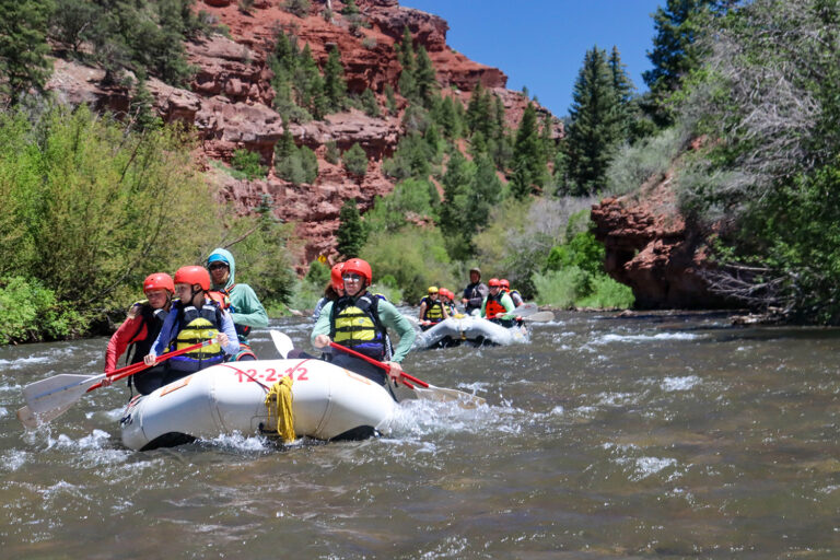 two boats drifting down the San Miguel River with red cliffs in the background - Mild to Wild