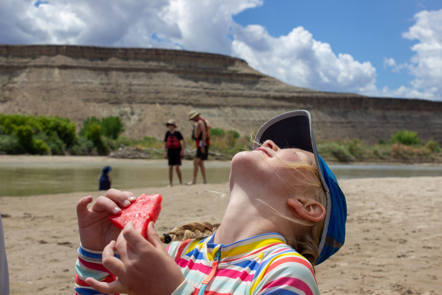 Girl laughing while eating watermelon on the beach in Desolation Canyon