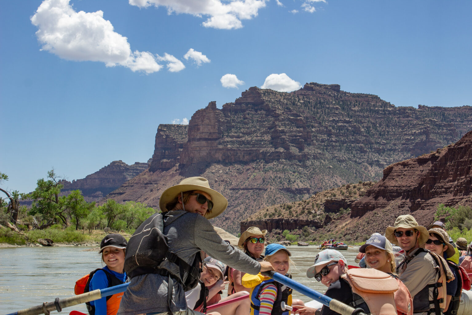 Desolation Canyon - Guide and guests smiling with mountains and river in background - Mild to Wild