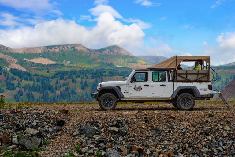 Jeep Gladiator parked ontop of Columbus basin in La Plata Canyon - Guests inside with scenic mountains and bluesky in the background - Mild to Wild