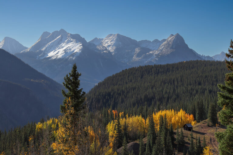 Wide shot of silverton fall colors with snowy mountains in background and cabin in foreground