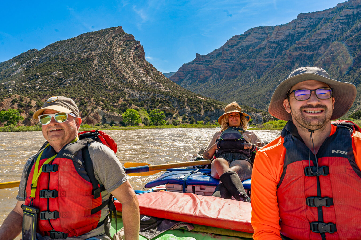 Guests and their river guide smiling as they row past the Mitten Park Fault in Dinosaur National Monument - Mild to Wild