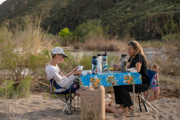 Two people play cards at a table in camp