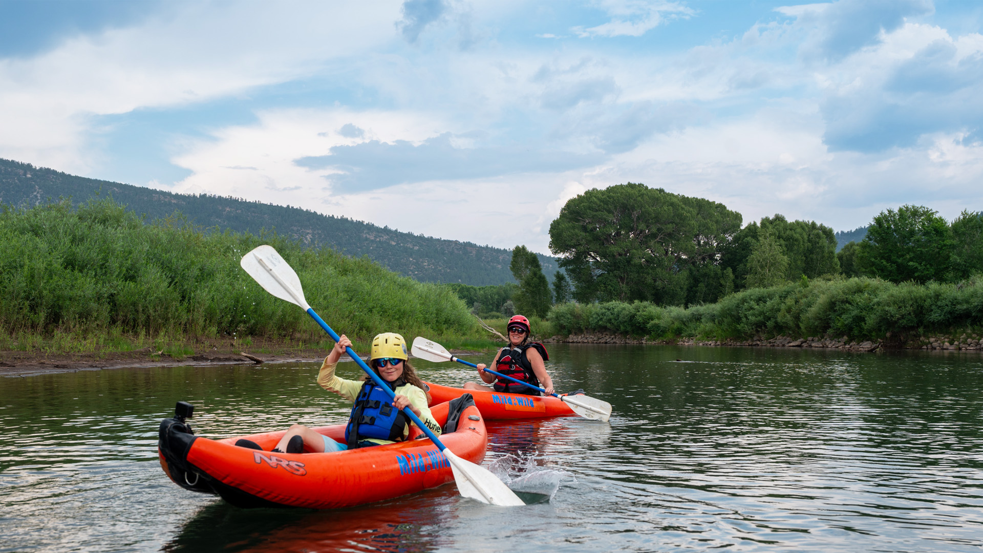 Wide shot of two people in Inflatable Kayaks on the Lower Animas River - Scenicm ountain background